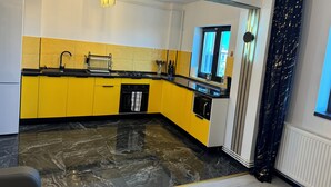A modern kitchen with yellow cabinets, a black countertop, a stove, and a window with a view.