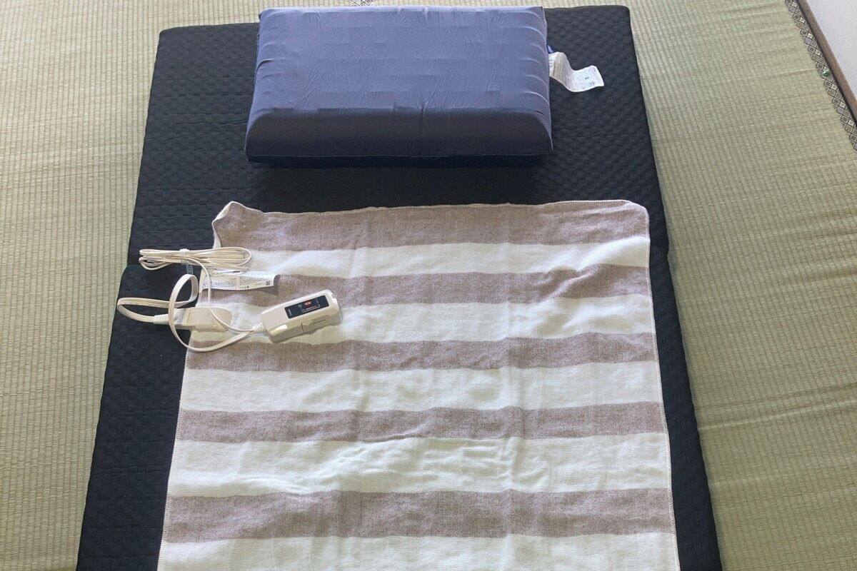 Una cama con un edredón a rayas, una almohada y un control remoto sobre un colchón negro.