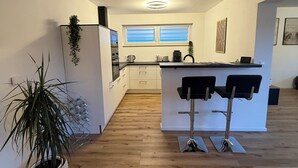 Una cucina moderna con isola centrale, mobili bianchi e una pianta in vaso.