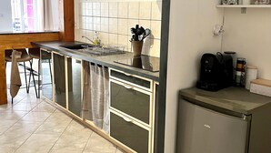 A modern kitchen with a built-in island, stainless steel appliances, and a wooden ceiling. - Cosy, modern studio - Gard (Saint-Ambroix)