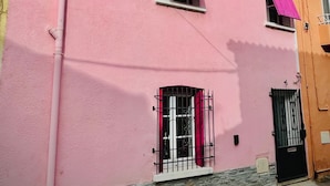 A pink building with two windows, a stone base, and a black gate. - Cosy, modern studio - Gard (Saint-Ambroix)