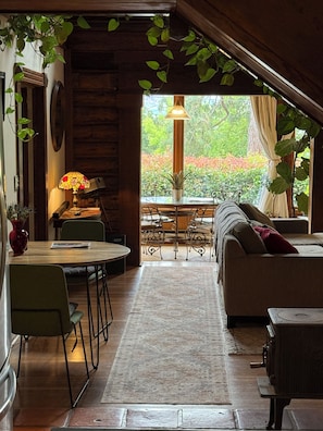 A cozy interior with a dining area, sofa, and a view of greenery outside.