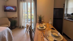 En matplats med ett bord dukat för två personer, en soffa, en tv som är monterad på väggen och en utsikt genom fönstret.