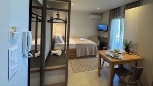 Ett hotellrum med en säng, en TV, ett matbord med stolar och en spegel.