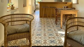 Um corredor amplo com área de cozinha, móveis de vime e piso estampado.