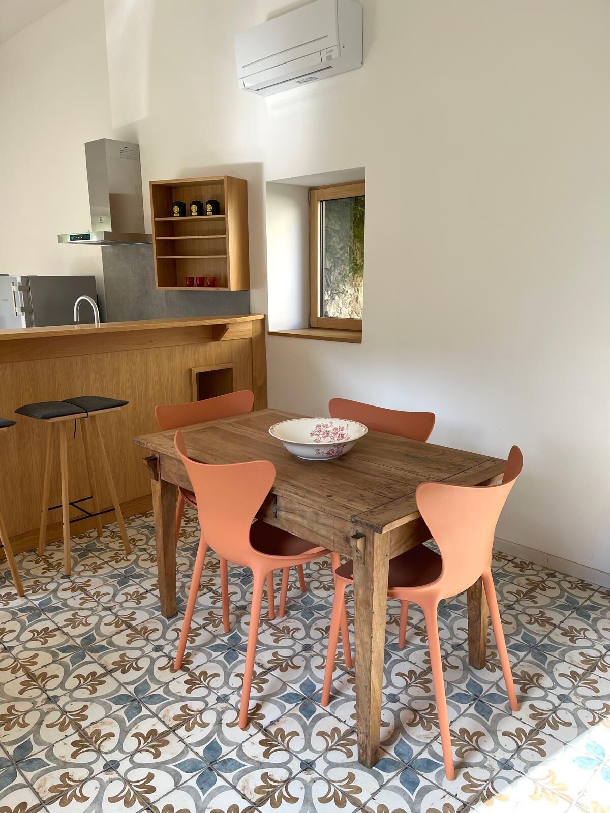 A kitchen with a wooden table and chairs, a window, and a built-in shelf.