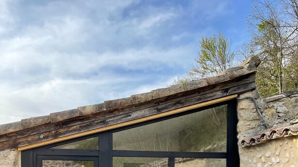 Casa de banho moderna com uma banheira grande, divisória de vidro e parede exterior em pedra.