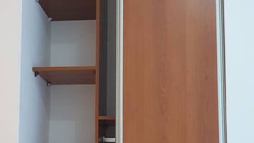 A wooden wardrobe with a mirrored door, a shelf, and a drawer.