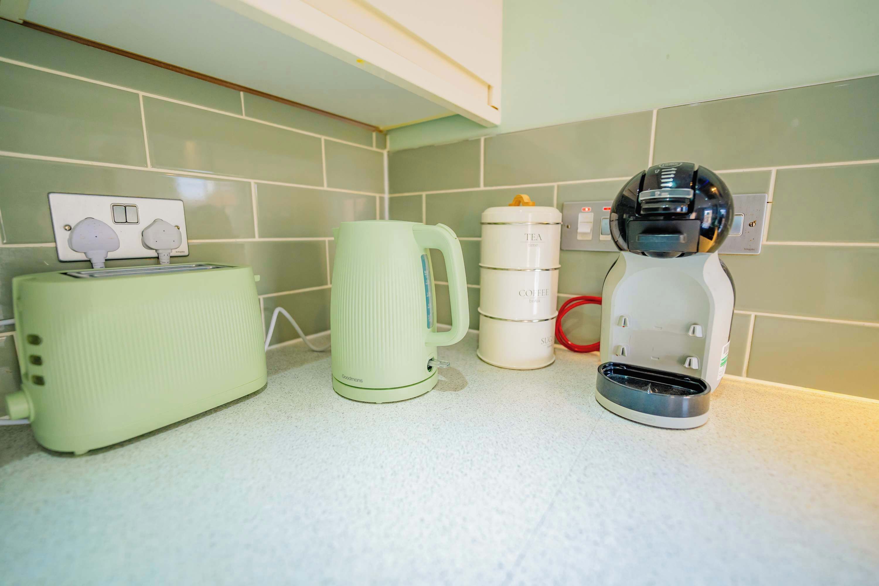 A kitchen with a toaster, a coffee maker, and a mug on the counter.