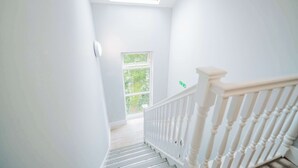A staircase with white railings leading to a landing with a skylight and a window. - Central Gloucestershire Flat 1 Bedroom  Sleeps 6 (Gloucestershire)