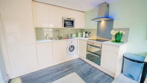 A modern kitchen with a built-in washing machine, oven, and microwave. - Central Gloucestershire Flat 1 Bedroom  Sleeps 6 (Gloucestershire)