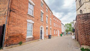 A brick building with a large arched doorway, a small window, and a trash bin. - Central Gloucestershire Flat 1 Bedroom  Sleeps 6 (Gloucestershire)