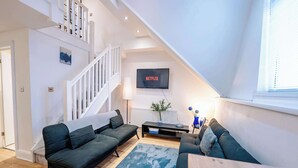 A modern living room with a staircase, a flat-screen TV, and a dining area. - Elegant Cardiff Bay Flat Spacious & Comfortable (Cardiff)