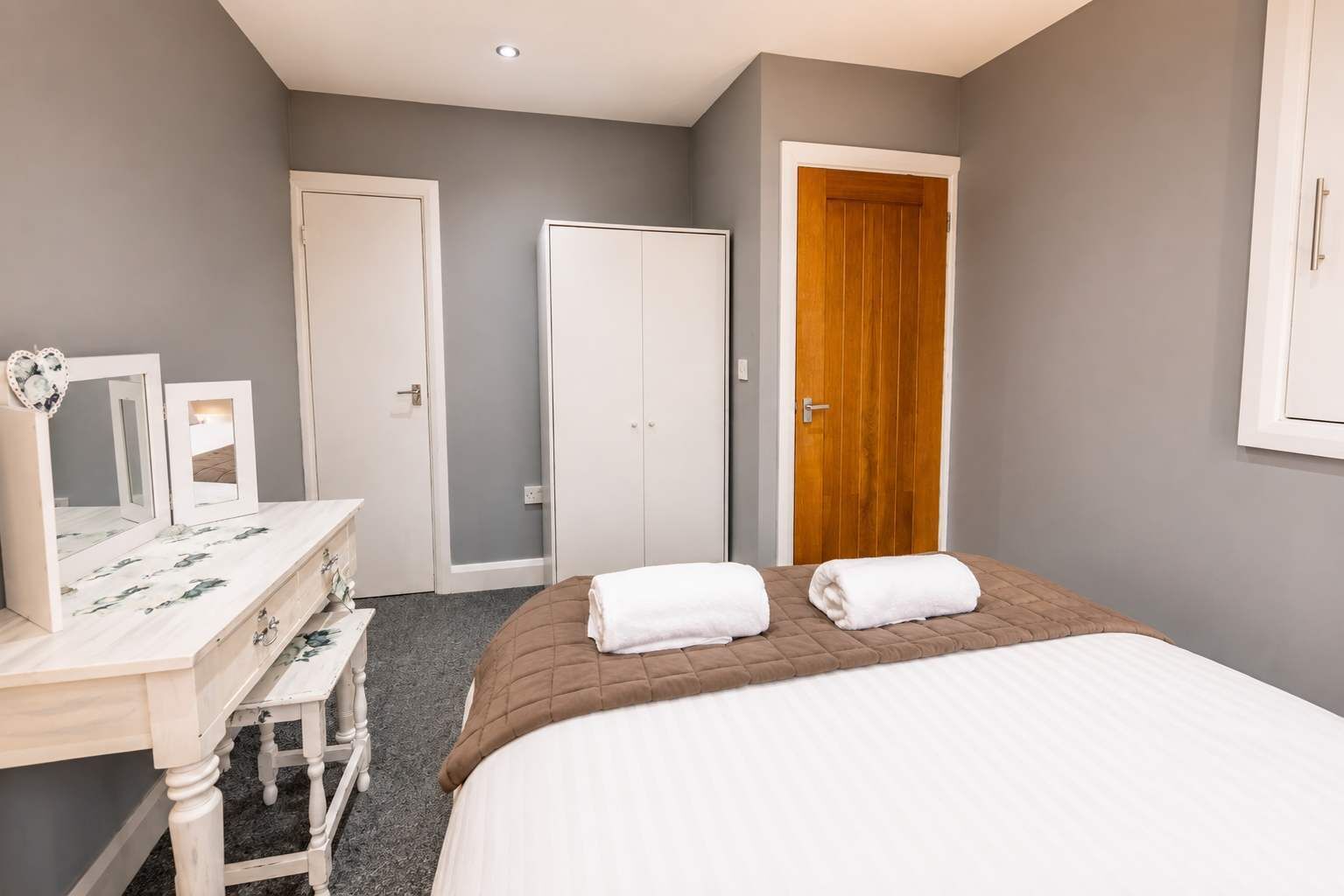 A bedroom with a bed, a dresser, a mirror, and a door.
