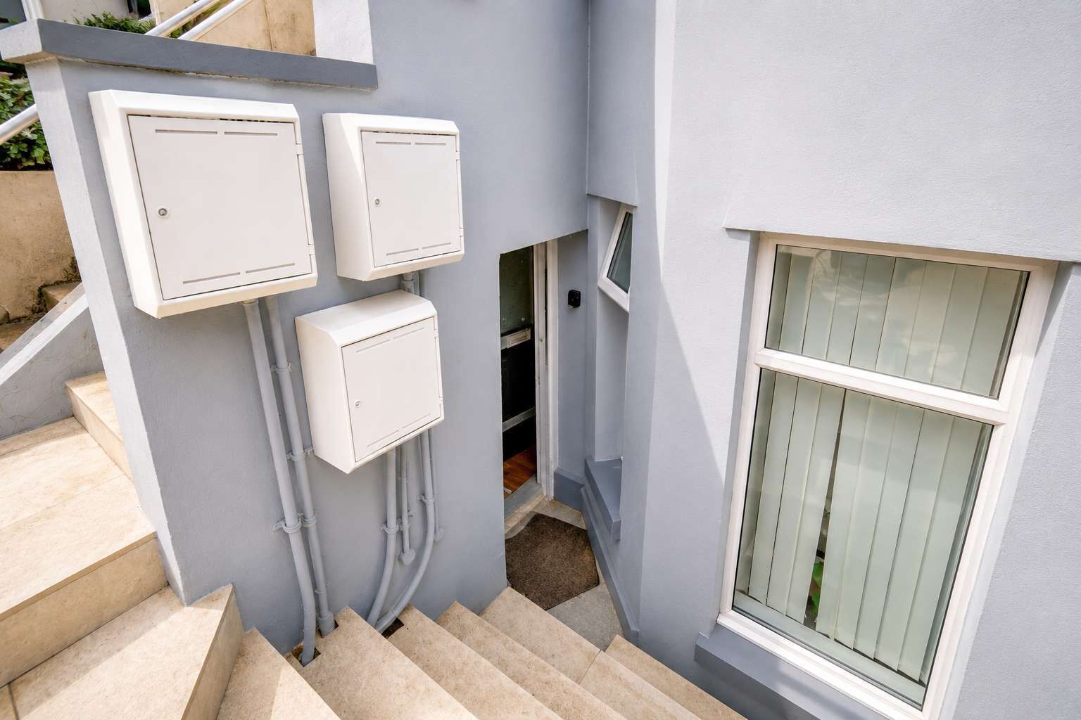 A staircase leading to a landing with three electrical boxes mounted on the wall.