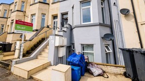 Um prédio residencial com uma placa de 'Vendido', uma escadaria e uma antena parabólica.