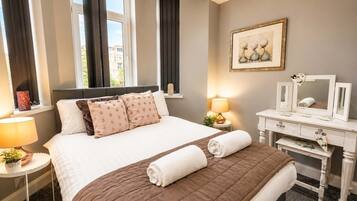 Ein Hotelzimmer mit einem Bett, Nachttischlampen, einem Schminktisch und einem Fenster mit Vorhängen.