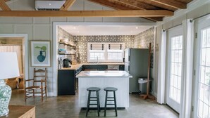 Une cuisine dotée d’un îlot central, de tabourets de bar, d’un plafond en bois et d’un papier peint à motifs.