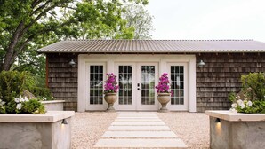 Un bâtiment rustique, avec une façade en bois, un toit en métal et un chemin de gravier menant à un ensemble de portes doubles.