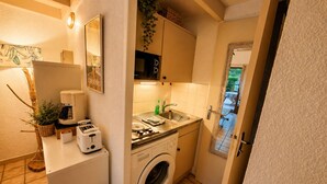 A compact kitchen with a washing machine, a coffee maker, and a sink.