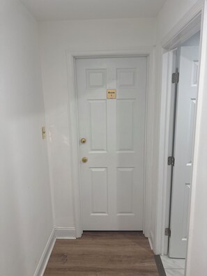A white door with a sign reading 'Room 1' and a keyhole. -  1  bedroom in a basement with share bathroom and share kitchen (Waldorf)