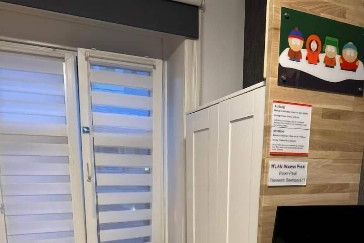 A room with a window, a desk, a chair, a wardrobe, and a bed.
