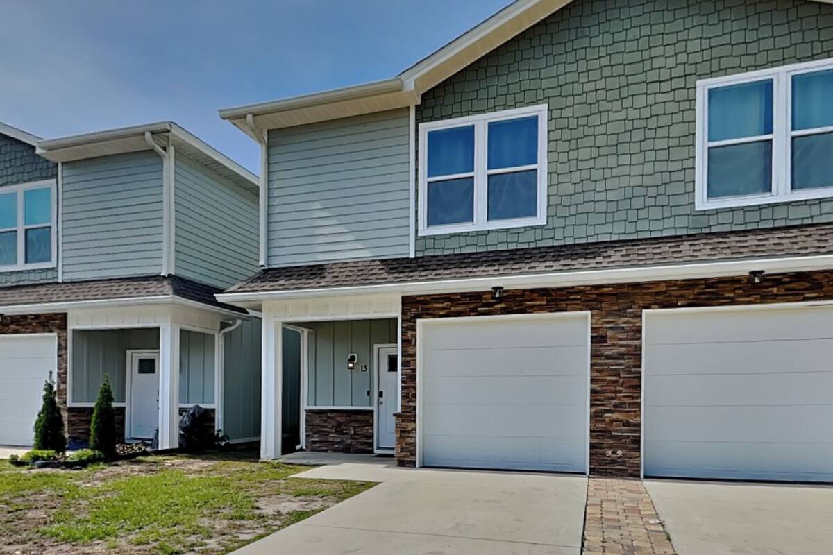 A two-story residential building with a garage, a covered porch, and a stone accent wall.