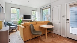 A modern living room with a sofa, chairs, a TV, and a dining table. - Nob Hill Stay, Reserved Garage Parking, Fireplace, Ground Floor Apartment (Portland)