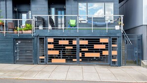 A modern building with a balcony, a gated entrance, and a number '215' on the wall. - Nob Hill Stay, Reserved Garage Parking, Fireplace, Ground Floor Apartment (Portland)