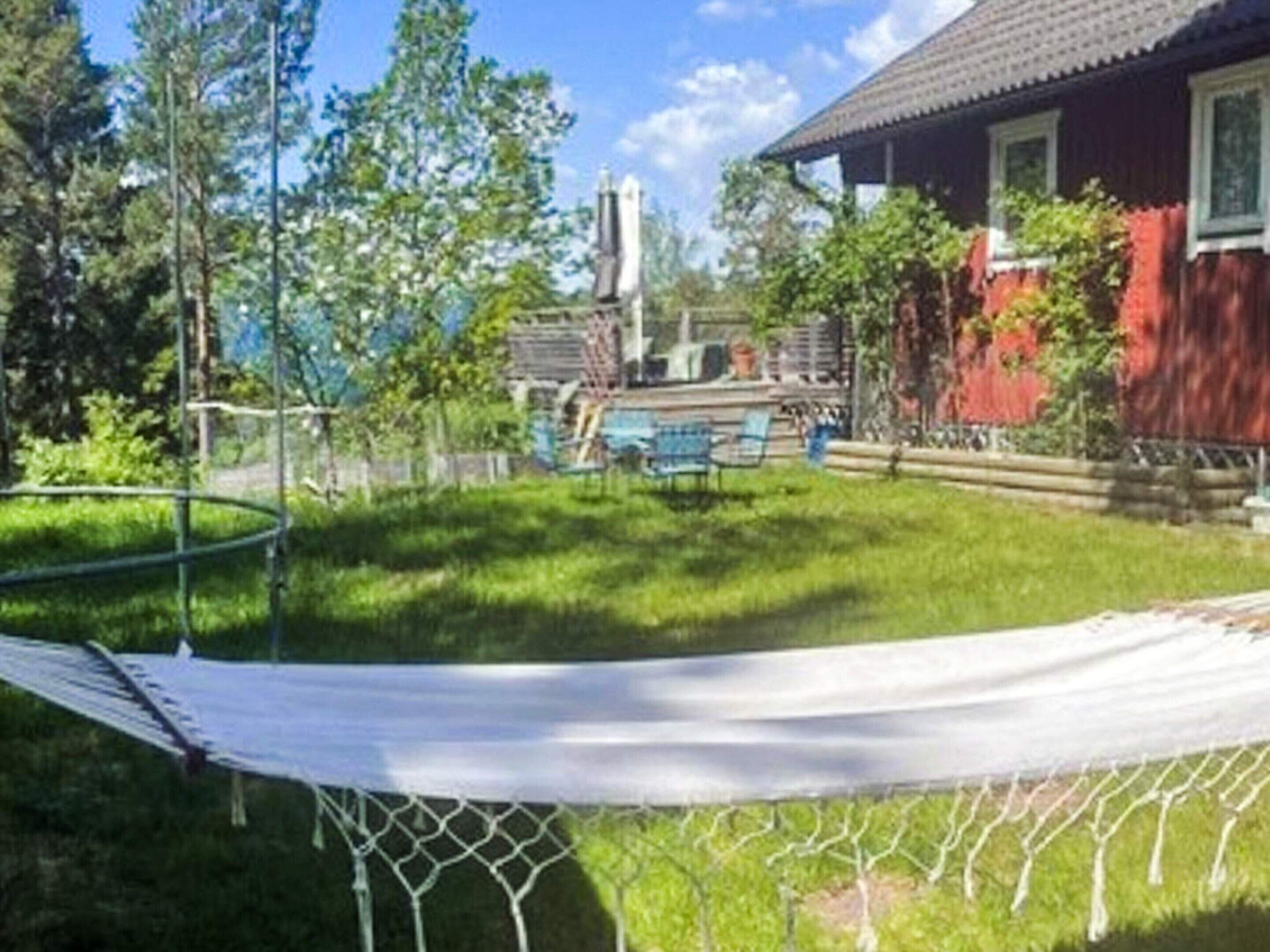 A red house with a white fence, a hammock, and a pool area.