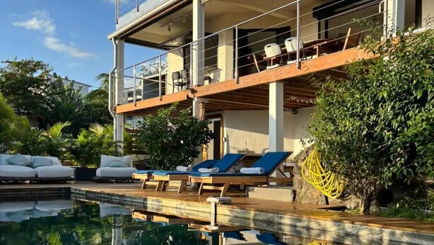 A two-story building with a pool, lounge chairs, and a wooden deck. - Villa Savane - Ocean view & Swimming pool, Reunion Island (Saint-Leu)