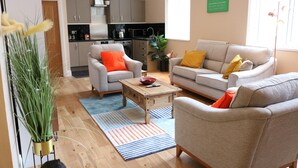 A living room with a sofa, armchair, coffee table, and a potted plant. - Stylish Comfort in the Heart of Sheffield (Sheffield)