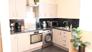 A kitchen with a washing machine, oven, microwave, and sink. - Stylish Comfort in the Heart of Sheffield (Sheffield)