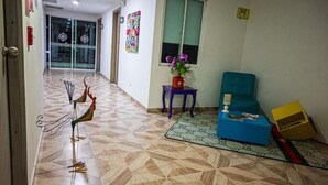 A hotel lobby with a geometric patterned floor, a blue sofa, a purple side table, and a decorative metal sculpture. - Hotel Veneton  (Dosquebradas)