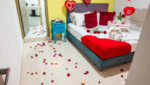 A bedroom with a bed, a nightstand, a dresser, and a bathroom visible in the background. - Hotel Veneton  (Dosquebradas)