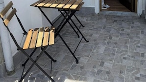 A small outdoor patio with a wooden table and chairs, a window, and a door leading to an interior space. - Tuscan Villa Retreat in San Romano (Montopoli in Val d'Arno)