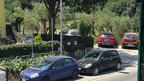 A street scene with parked cars, a yellow building, and greenery. - Tuscan Villa Retreat in San Romano (Montopoli in Val d'Arno)