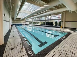En inomhuspool med tydligt markerade banor, ett kaklat golv och ett takfönster ovanför.
