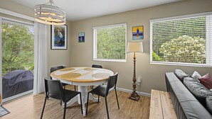 A dining area with a round table, chairs, a lamp, and a sofa. - Beach Please | Hot tub and Dog Friendly Sleeps 8 (Rockaway Beach)