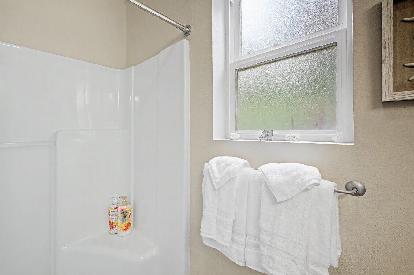 A bathroom with a shower, a window, and a towel rack with towels.