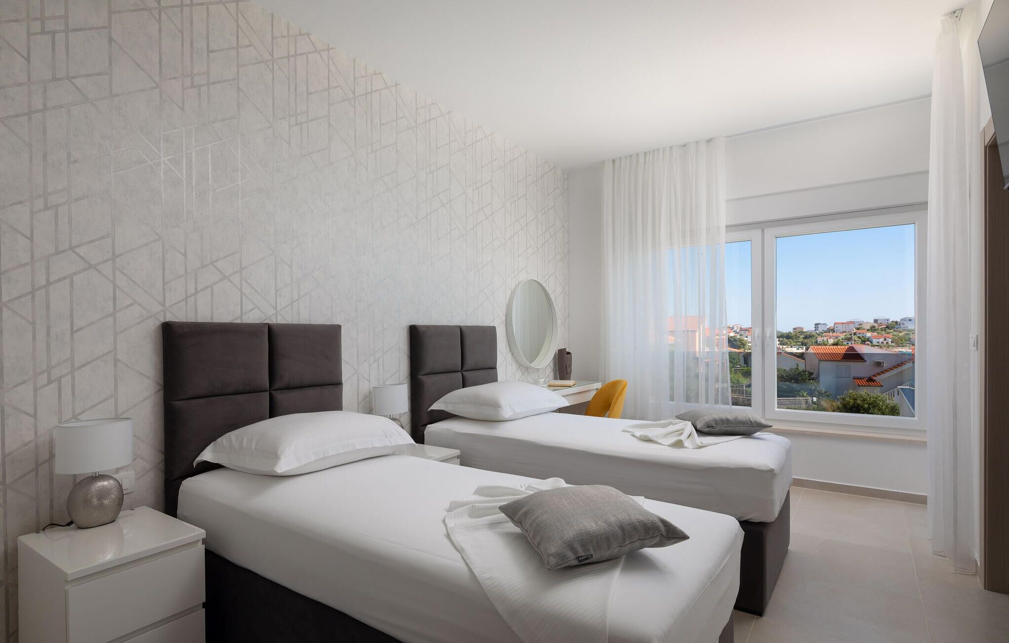 Une chambre d’hôtel avec deux lits, une grande fenêtre et un motif géométrique sur le mur.