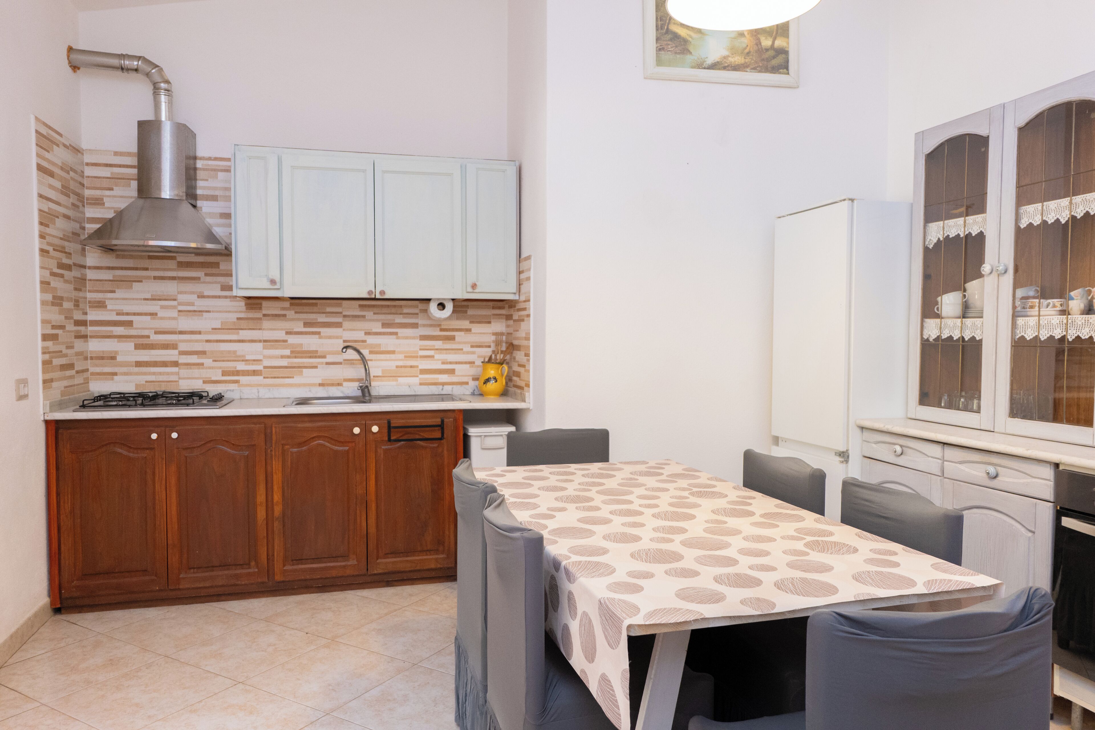 A compact kitchen with wooden cabinets, a gas stove, and a dining area with a table and chairs.