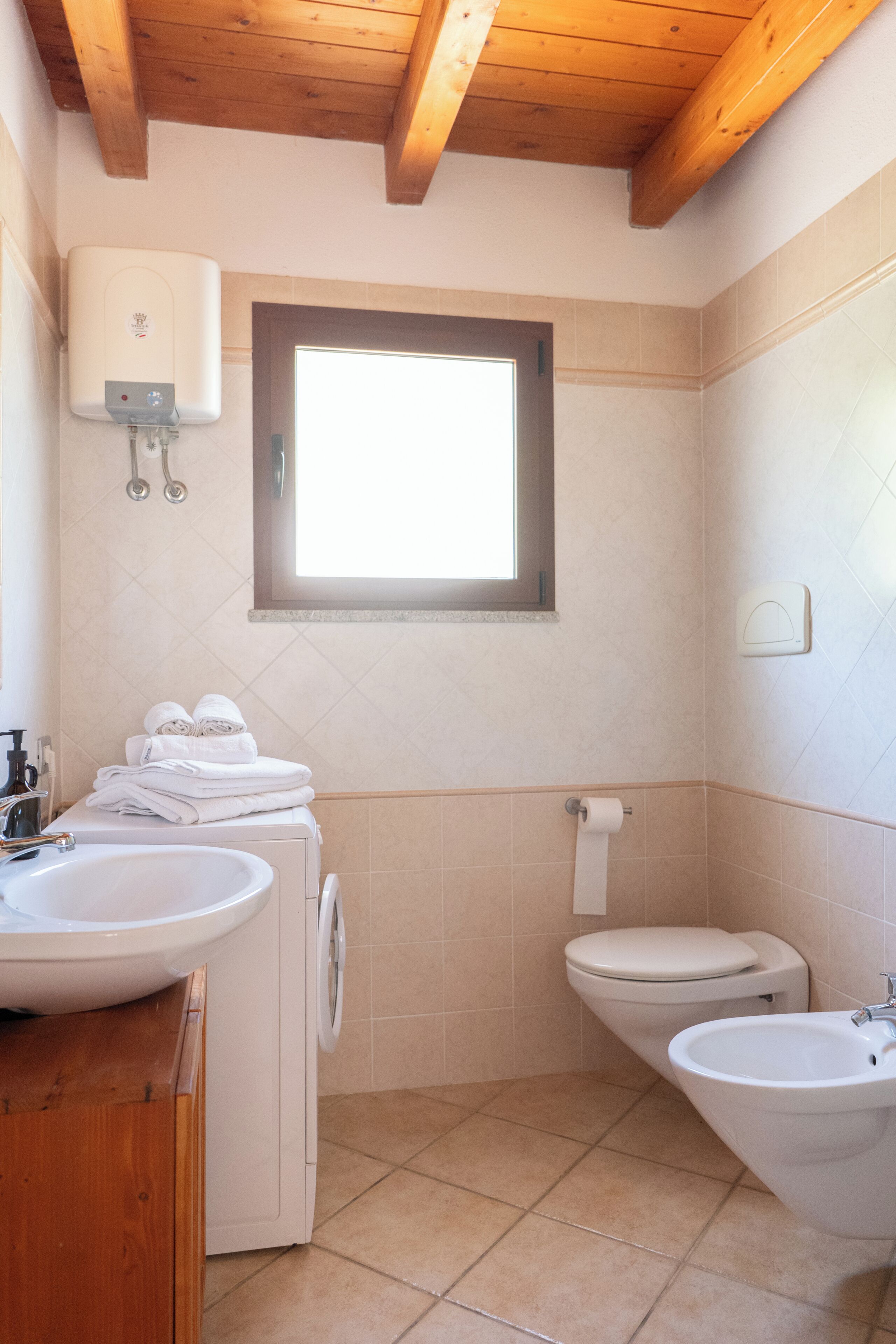 Een badkamer met een wastafel, toilet, bidet en een raam.