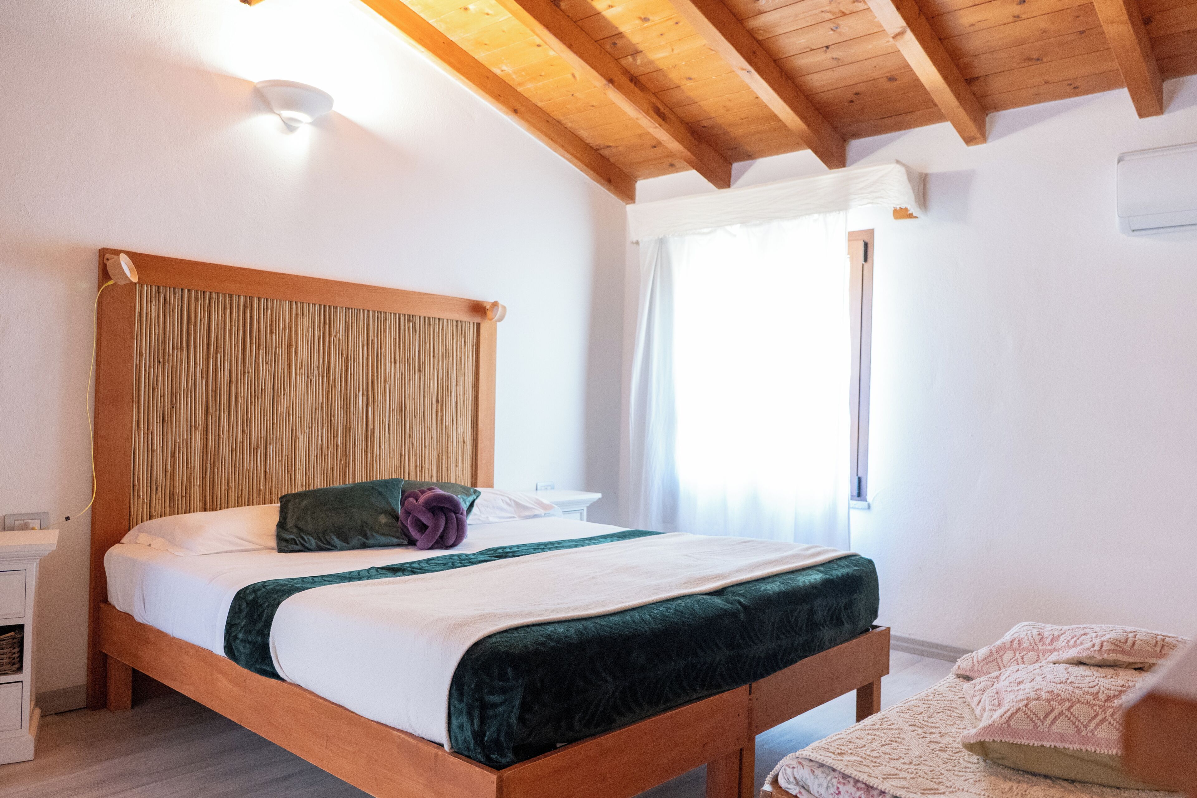 A wooden bed with a headboard, a bedside table, and a window with curtains.