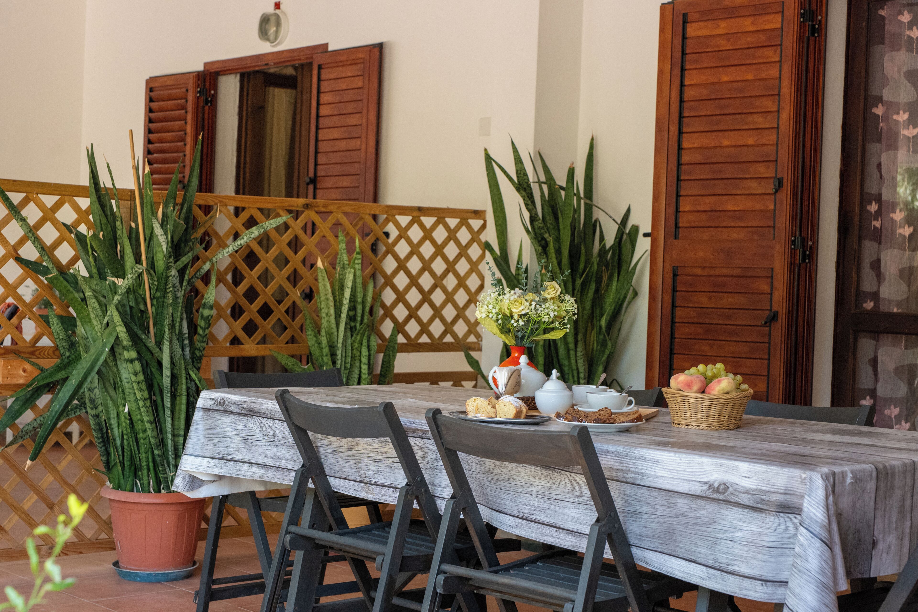 Una mesa con sillas, una cesta de fruta, un hervidor y una taza.