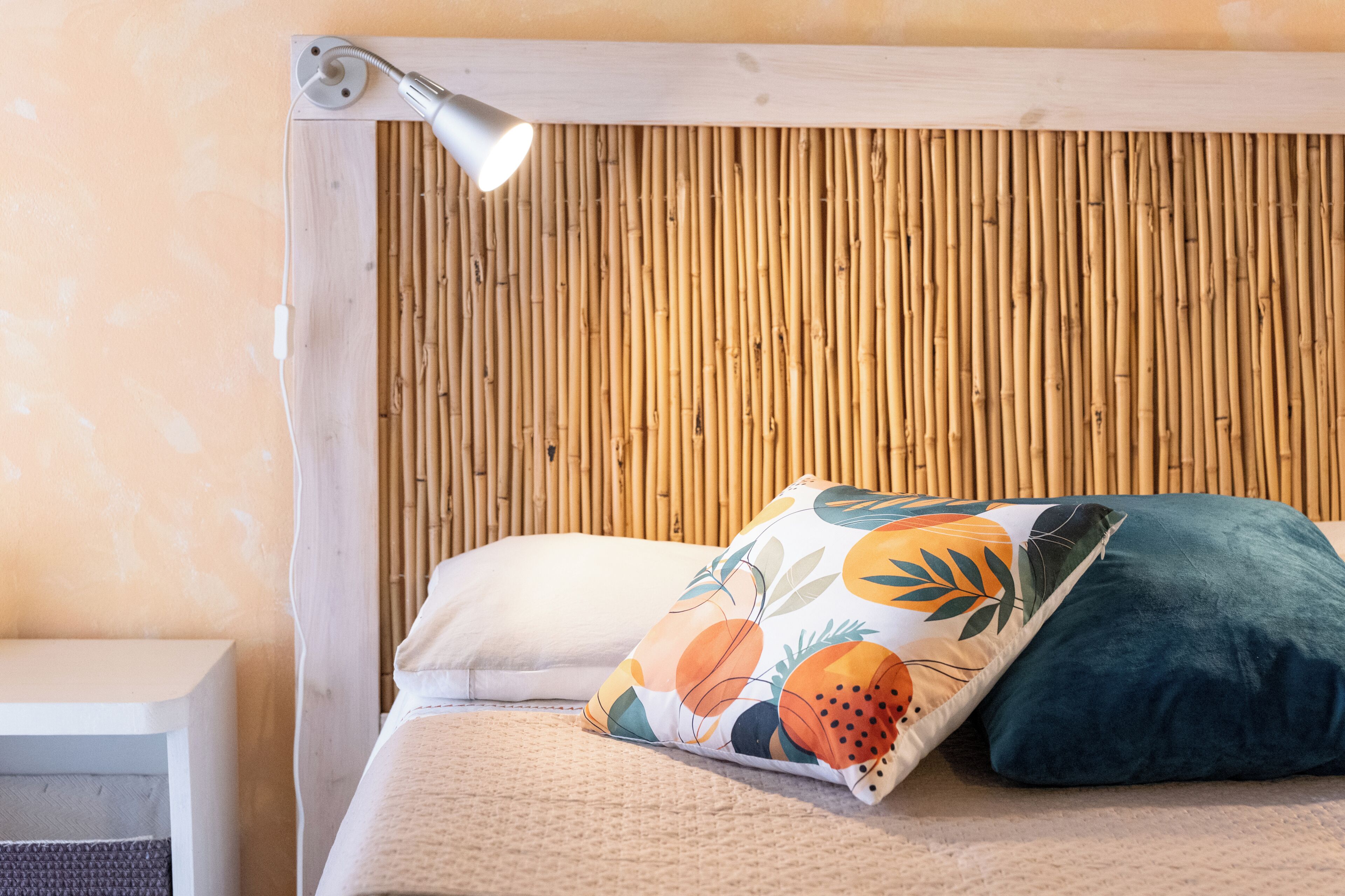A bed with a pillow and a bedside lamp.