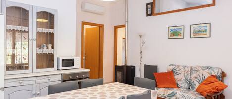 A compact living space with a dining table, sofa, and kitchenette.