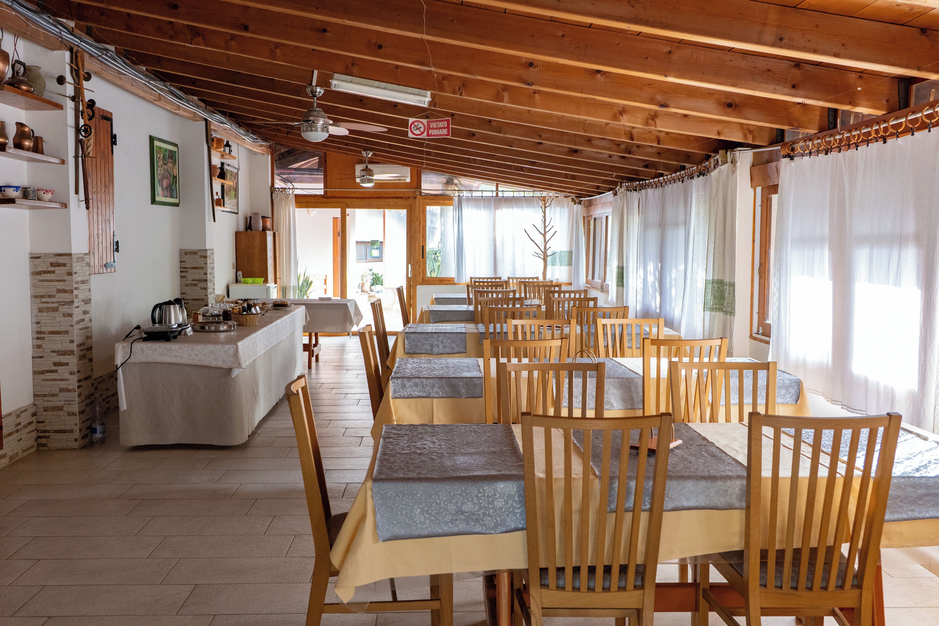 A dining area with wooden tables and chairs, a kitchen area with a stove and utensils, and a sign prohibiting smoking.