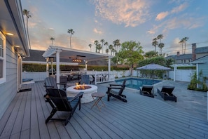 Eine Terrasse mit Gartenmöbeln, Feuerstelle und Pool.