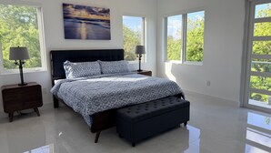 A modern bedroom with a large bed, two bedside tables, a bench, and large windows with a view of greenery. - #1 Enjoyable 2-bedroom condo with AC in charming Savannah (Savannah)